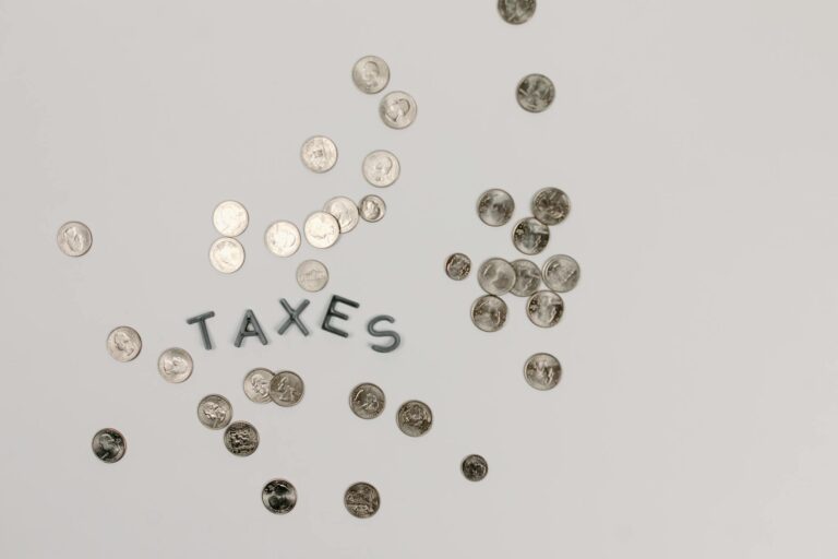 A visually striking flatlay of coins with 'Taxes' text on a white surface, ideal for financial concepts.